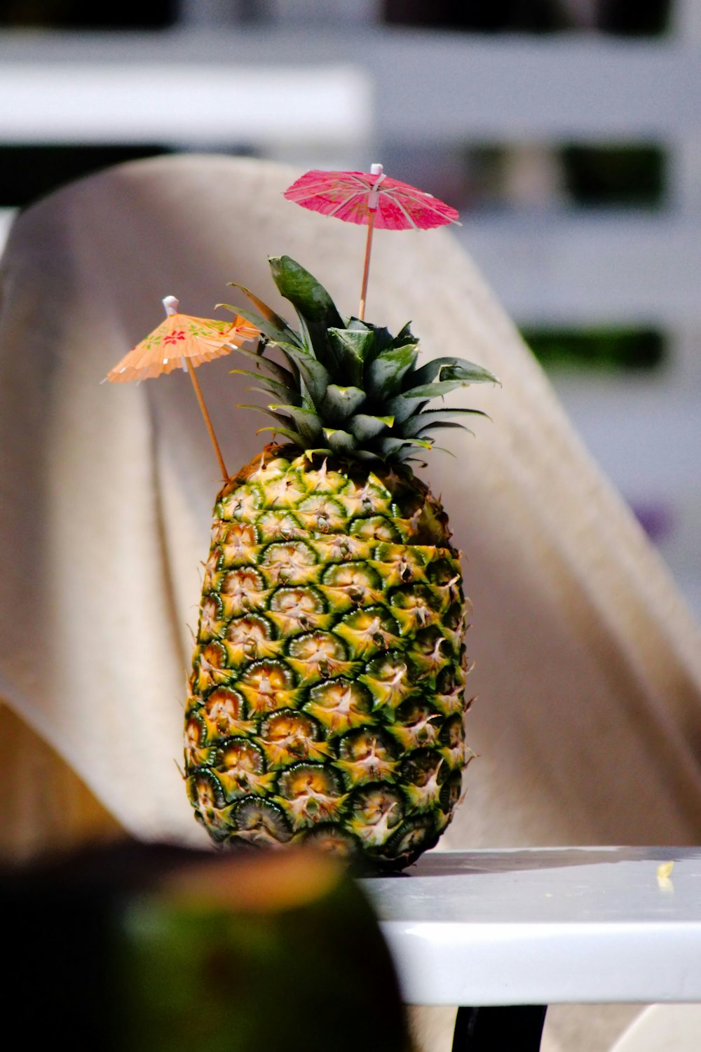 a pineapple sitting on a table with an umbrella