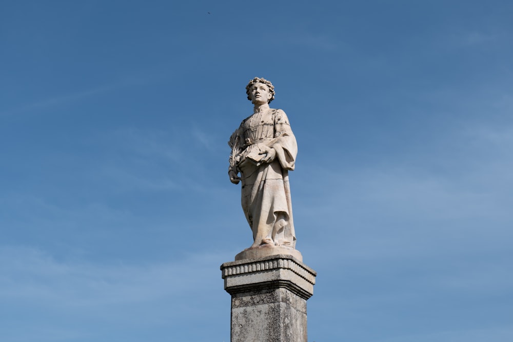 a statue of a man standing on top of a cement pillar