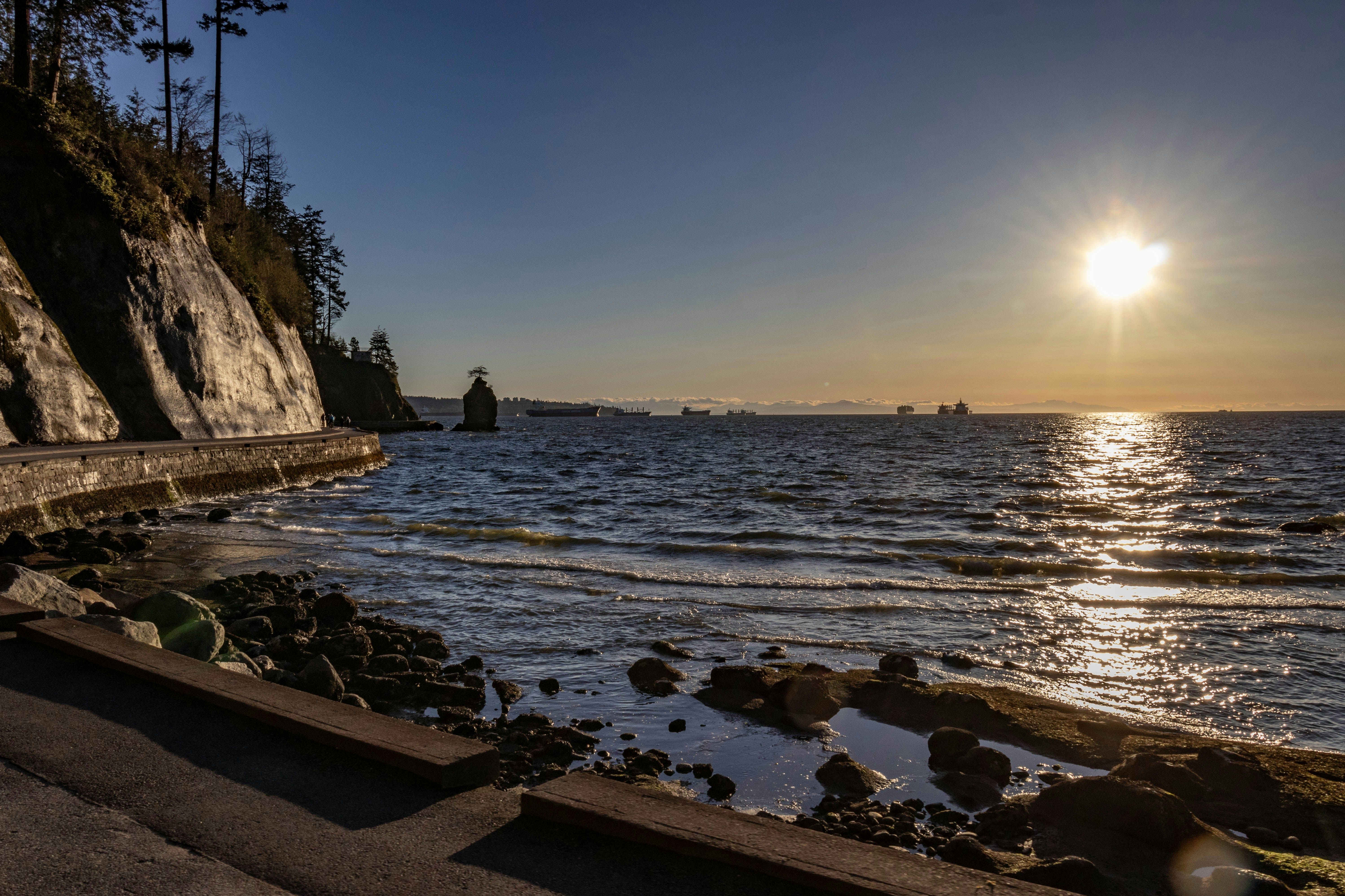 the sun is setting over the water at the beach
