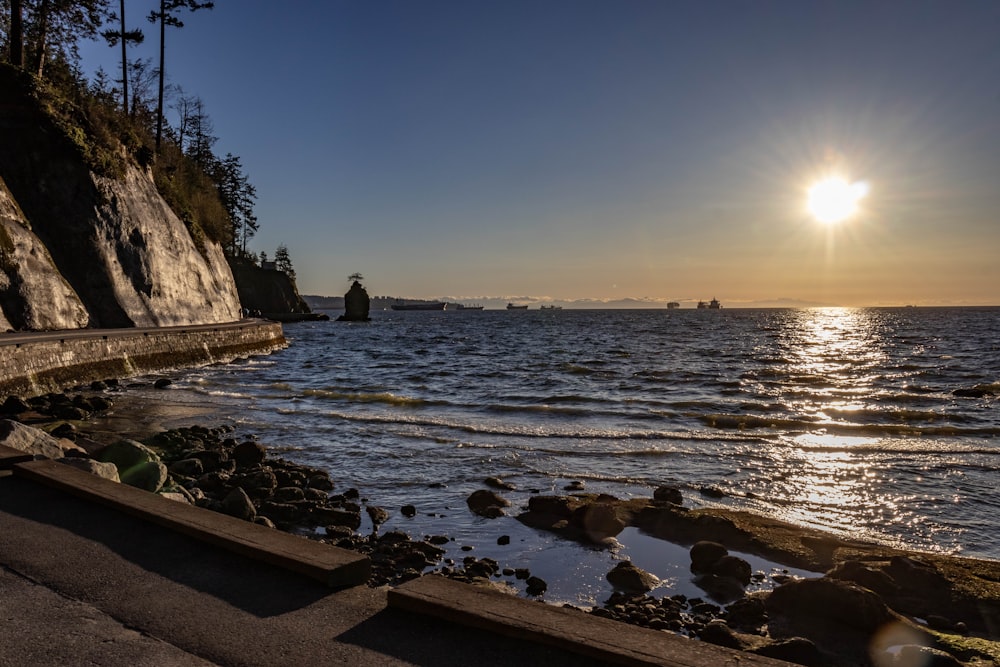 the sun is setting over the water at the beach