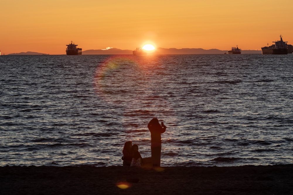 a couple of people sitting on a beach next to the ocean