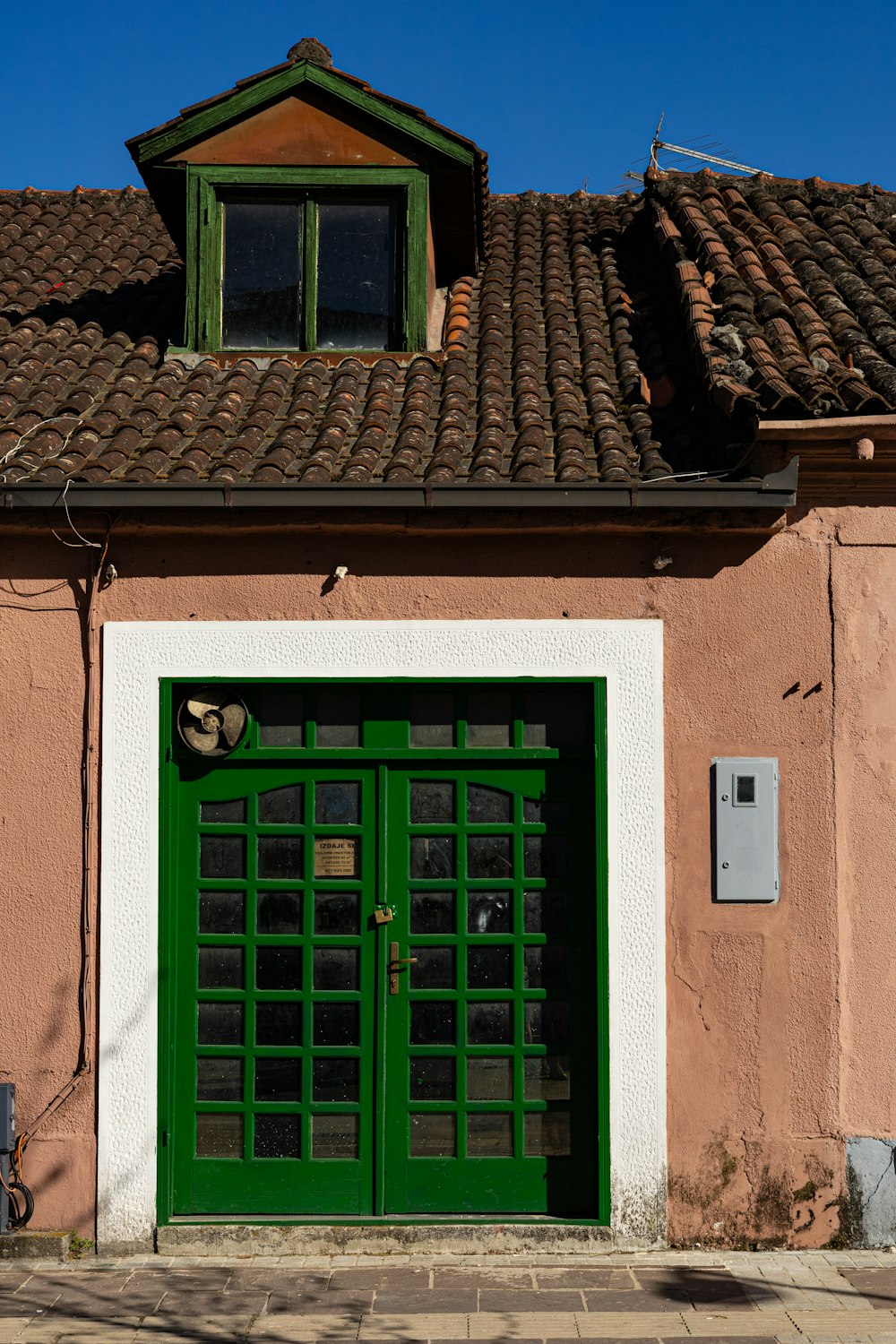 a green door on the side of a pink building