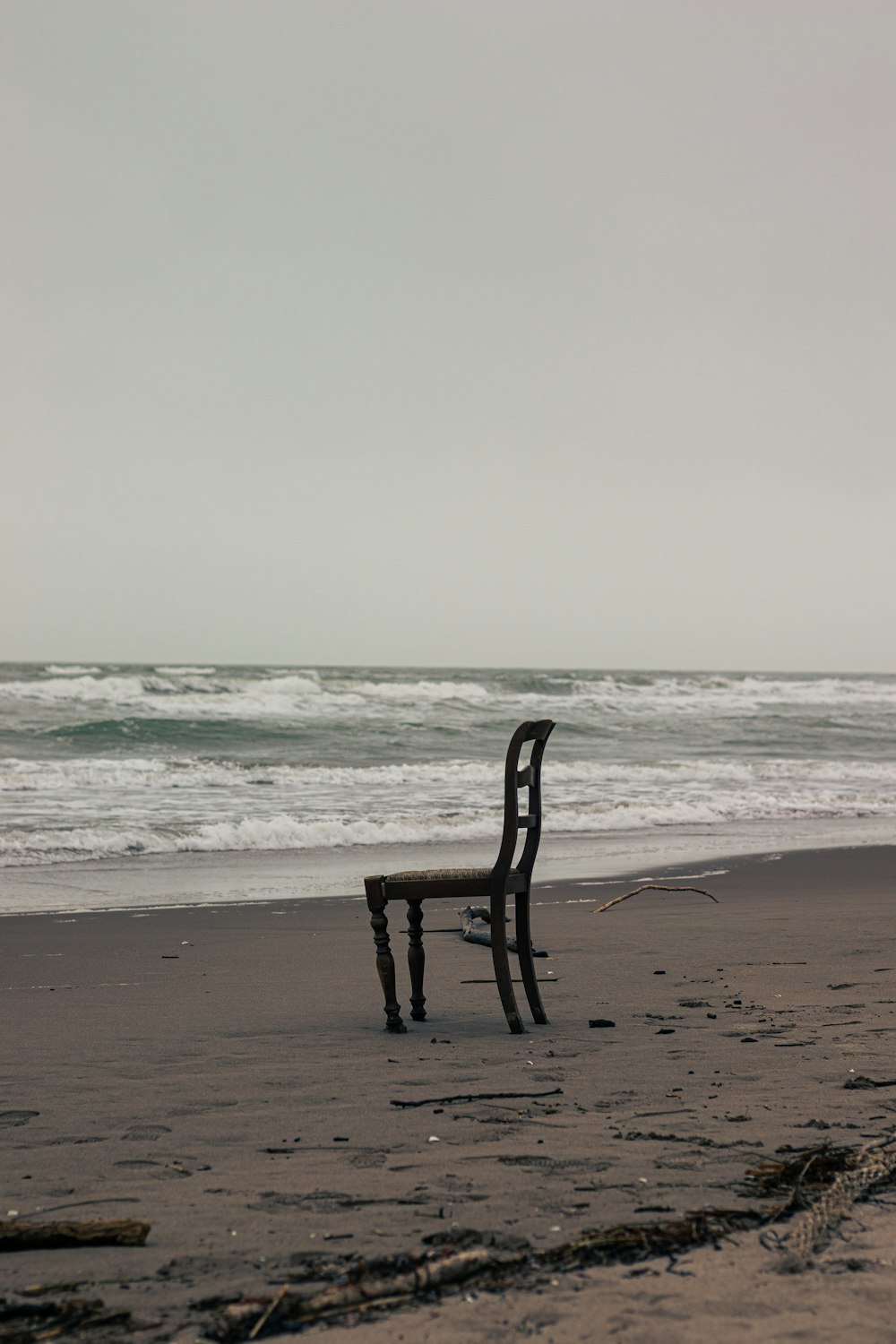 a wooden chair sitting on top of a sandy beach