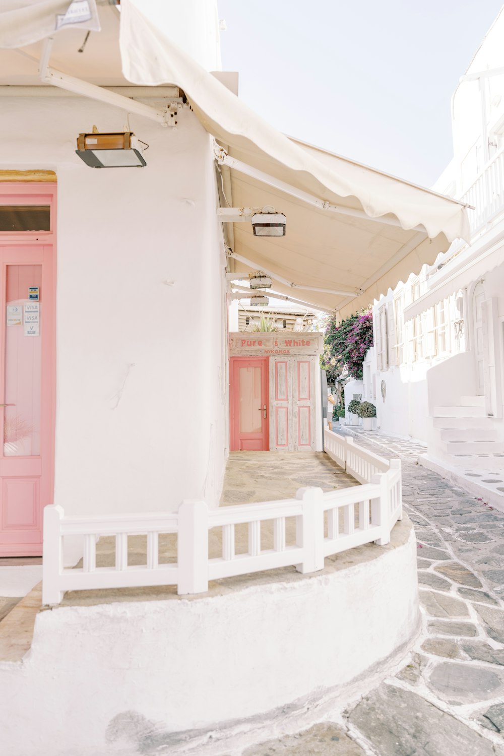 a white building with a pink door and a pink door