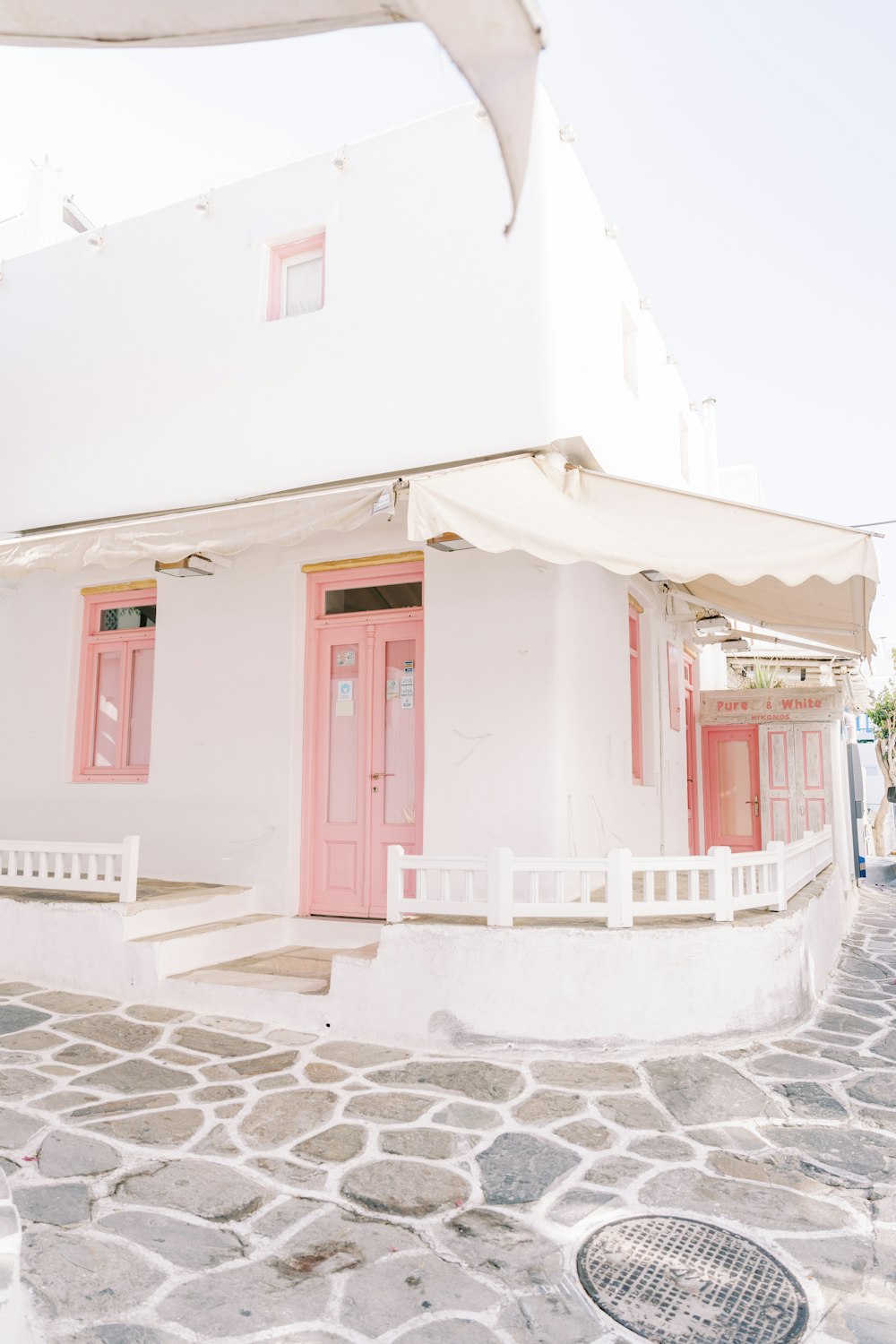 a white building with pink doors and a white fence