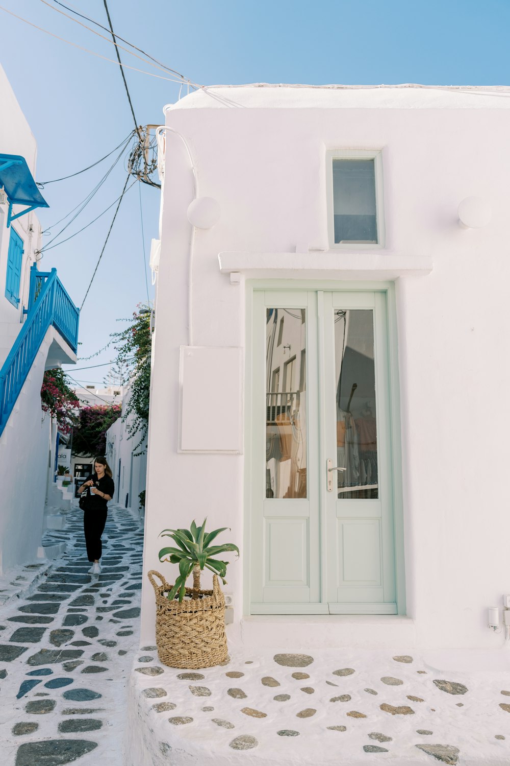 a woman walking down a street past a white building