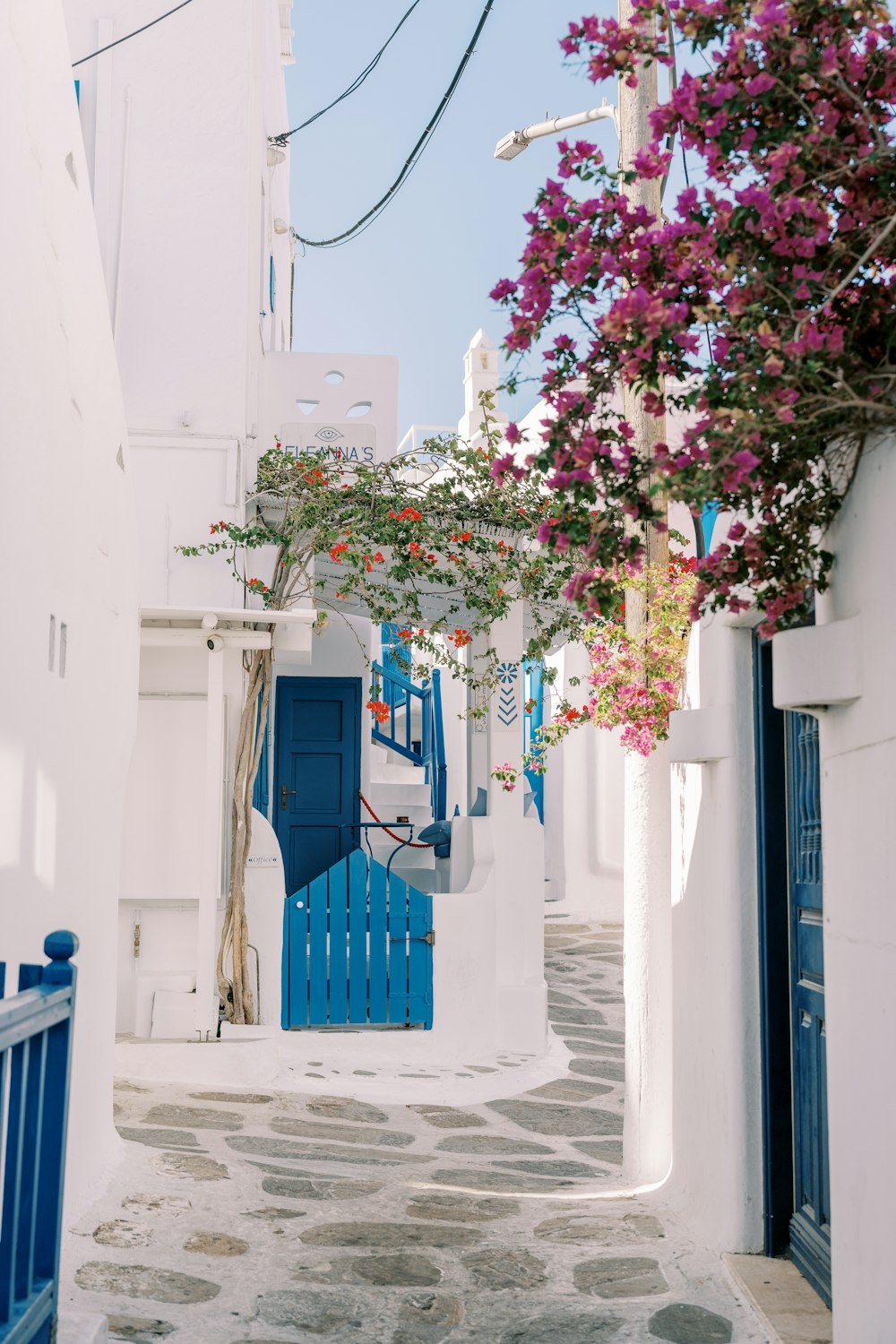 a narrow street with white buildings and blue doors
