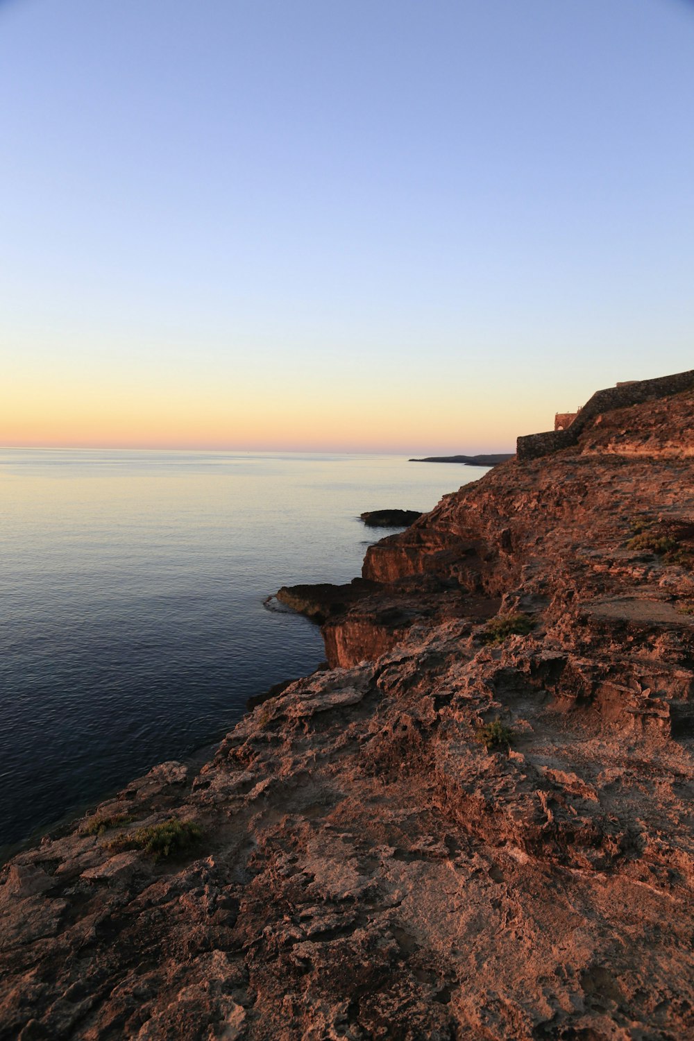 a bench sitting on the edge of a cliff overlooking the ocean