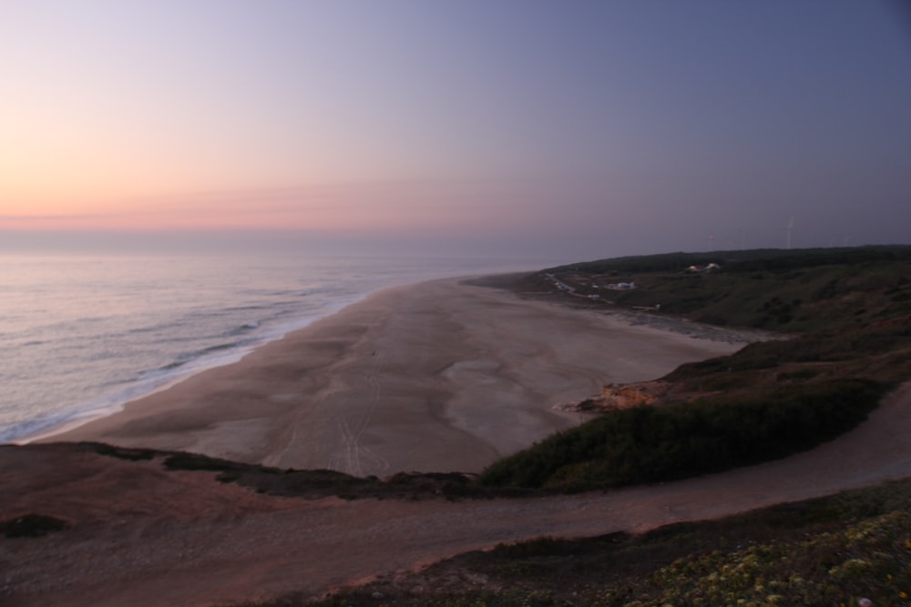 a view of a beach at sunset from a hill