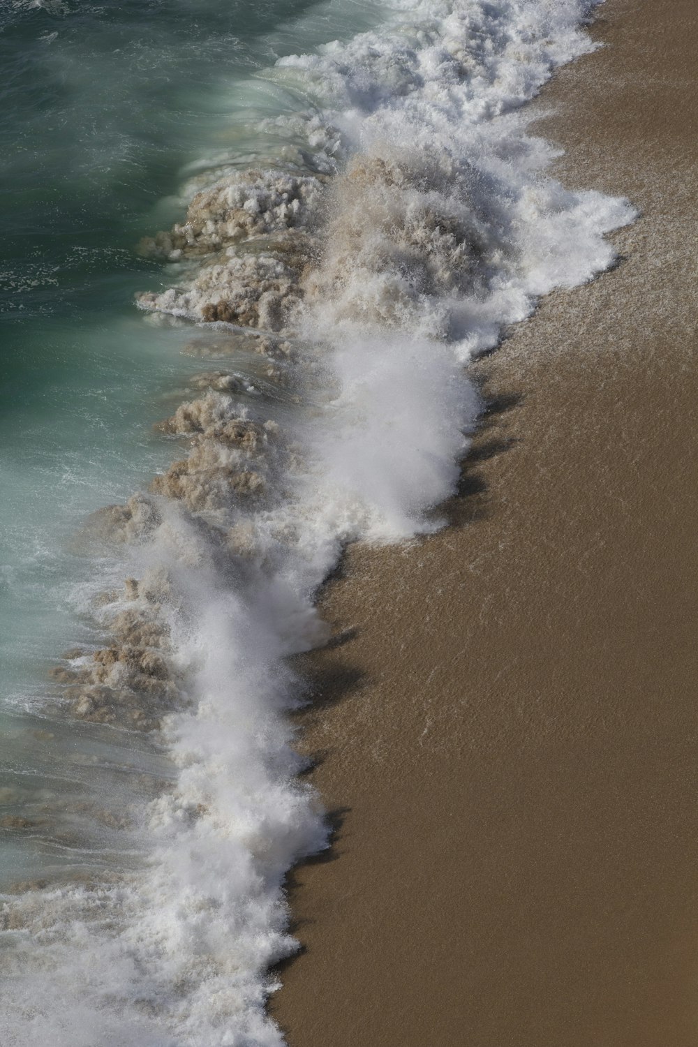 a wave is coming in to the shore of a beach
