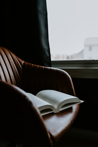 an open book sitting on top of a brown chair