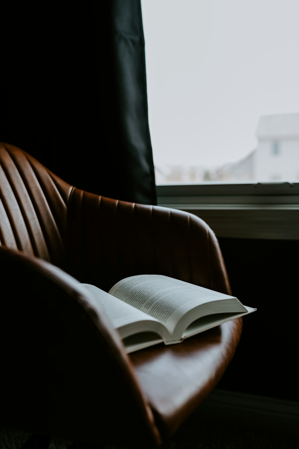 an open book sitting on top of a brown chair