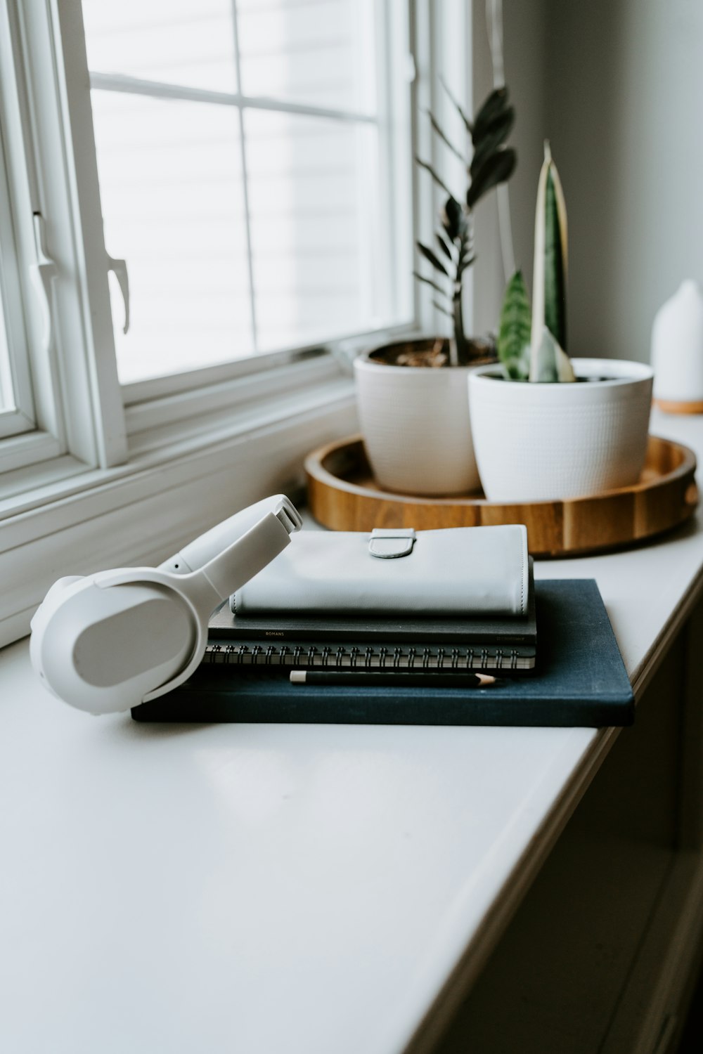 a desk with a notebook, headphones and a potted plant