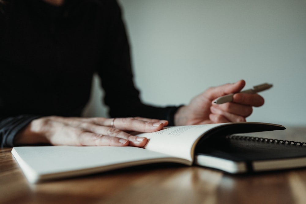 a person sitting at a table with a notebook and pen