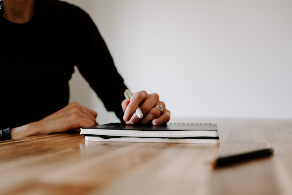 a person sitting at a table with a notebook and pen