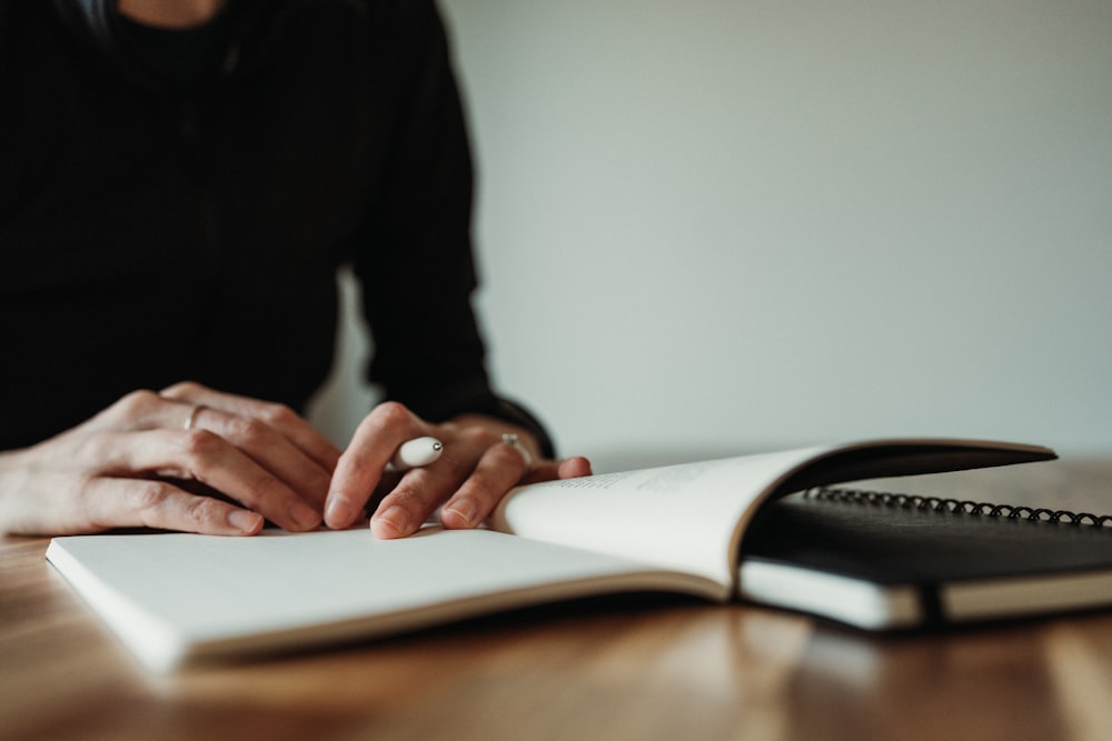 a person sitting at a table with a book and pen