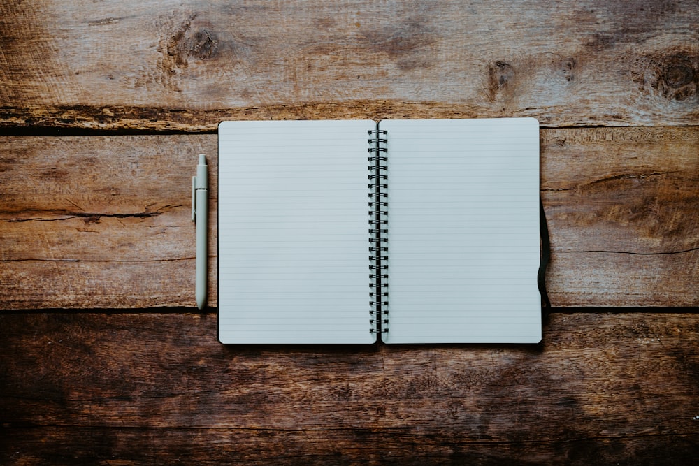 a notebook with a pen on top of a wooden table