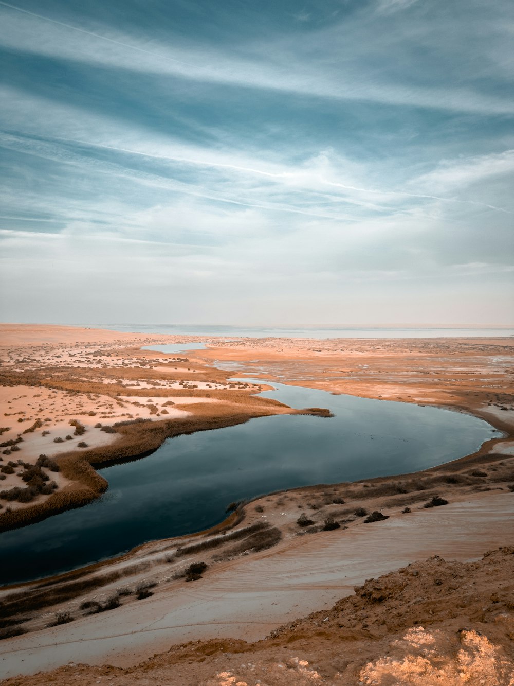 a body of water surrounded by desert land