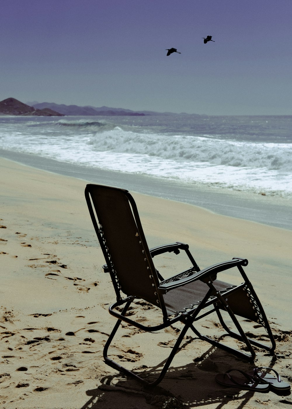 a lawn chair sitting on top of a sandy beach