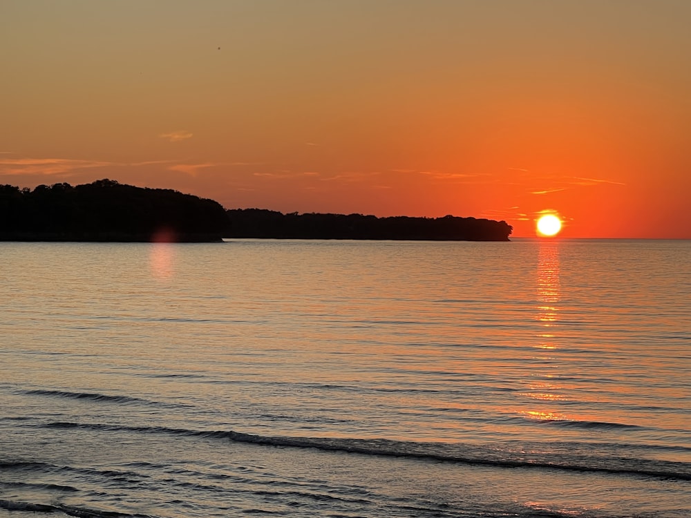 the sun is setting over the water at the beach