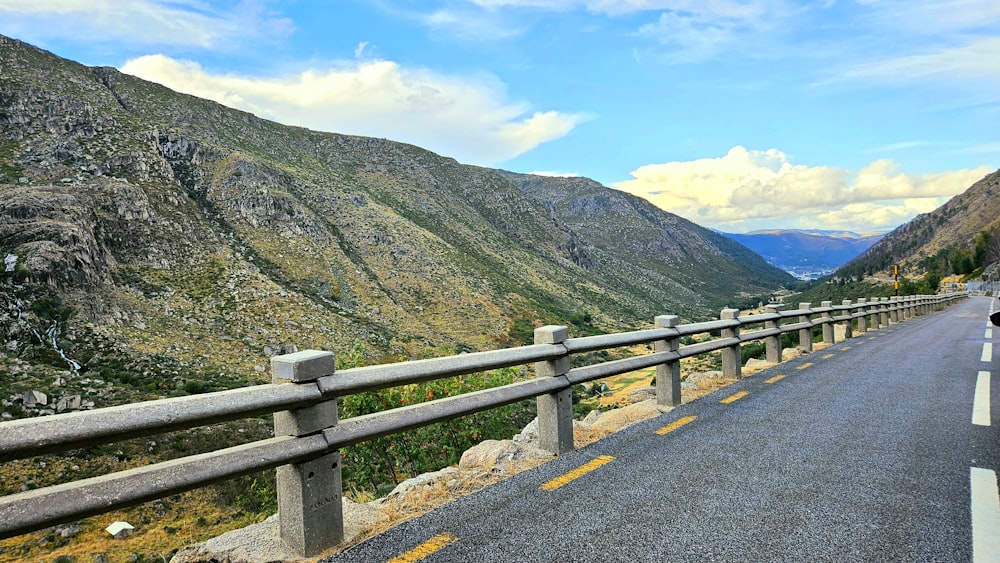 a man riding a motorcycle down a road next to a mountain