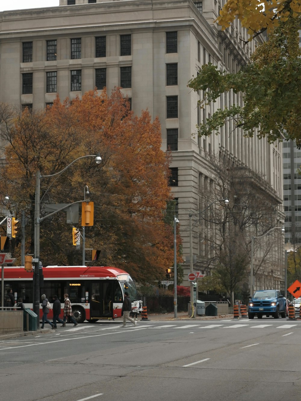 a red and white bus driving down a street next to tall buildings