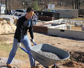 a man pushing a wheelbarrow filled with gravel