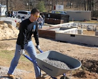 a man pushing a wheelbarrow filled with gravel
