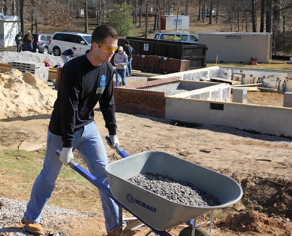 a man pushing a wheelbarrow filled with gravel