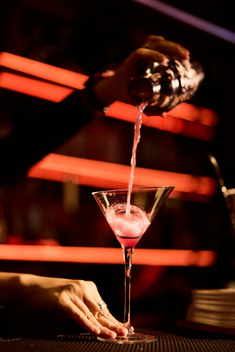 a person pouring a drink into a martini glass