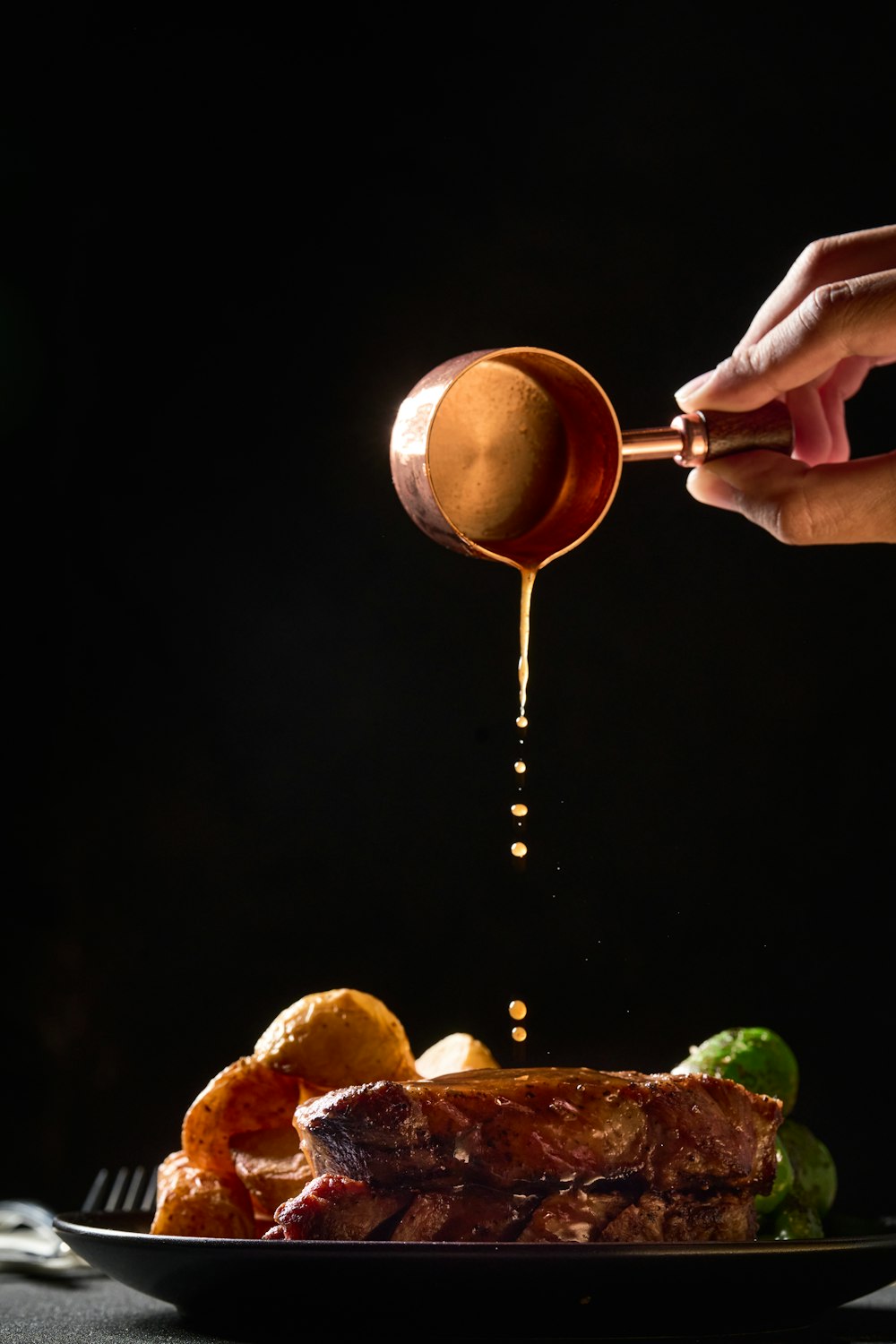 a person pouring sauce on a steak on a plate