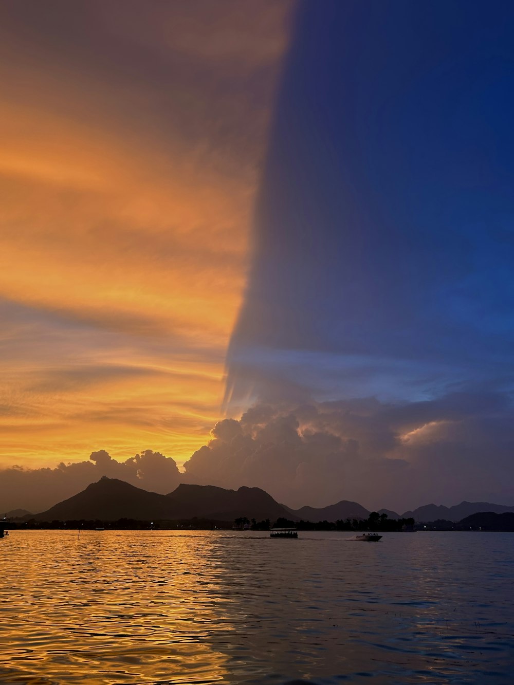 a sunset over a body of water with mountains in the background