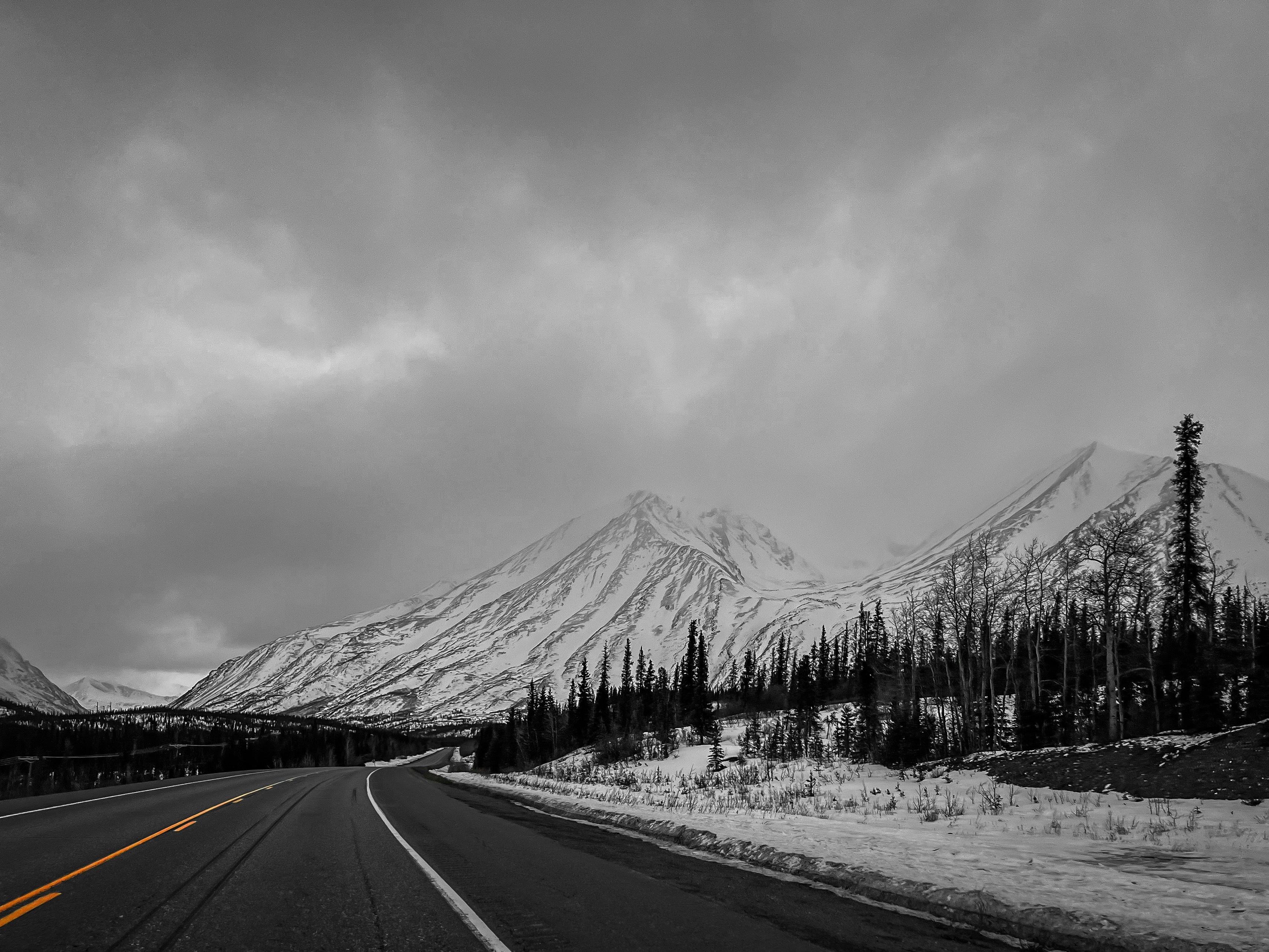 a black and white photo of a road with a mountain in the background