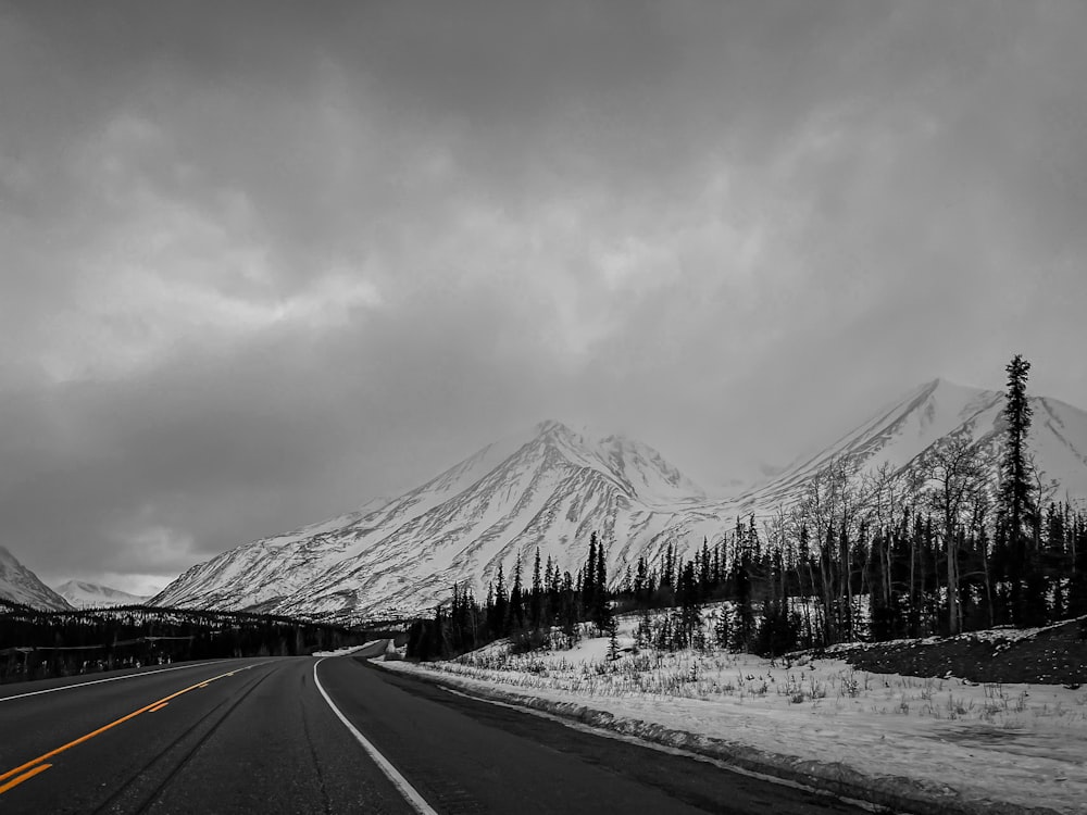 a black and white photo of a road with a mountain in the background