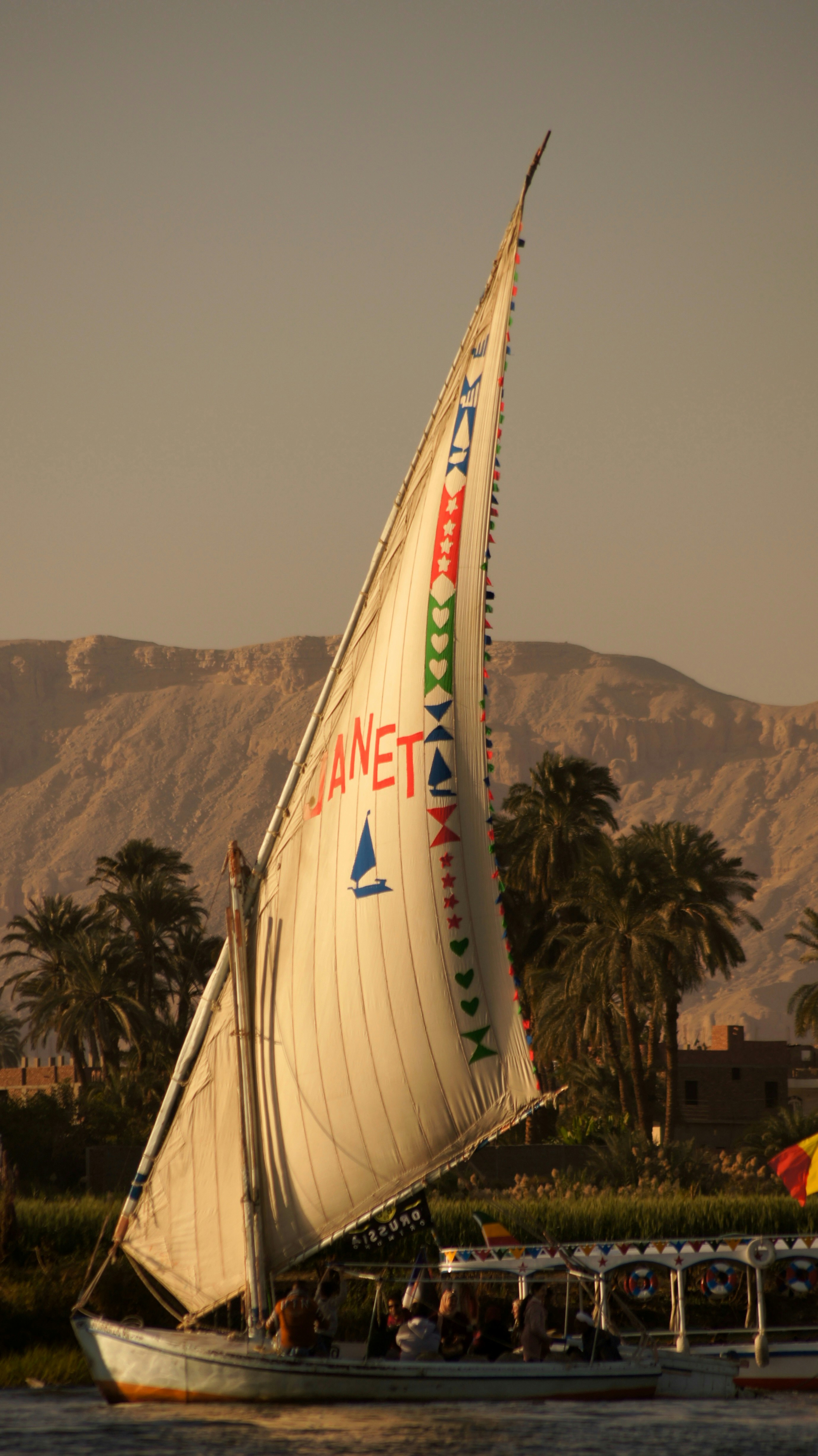 Traditional Egyptian felucca on Nile at sunset, warm golden reflections, peaceful water
