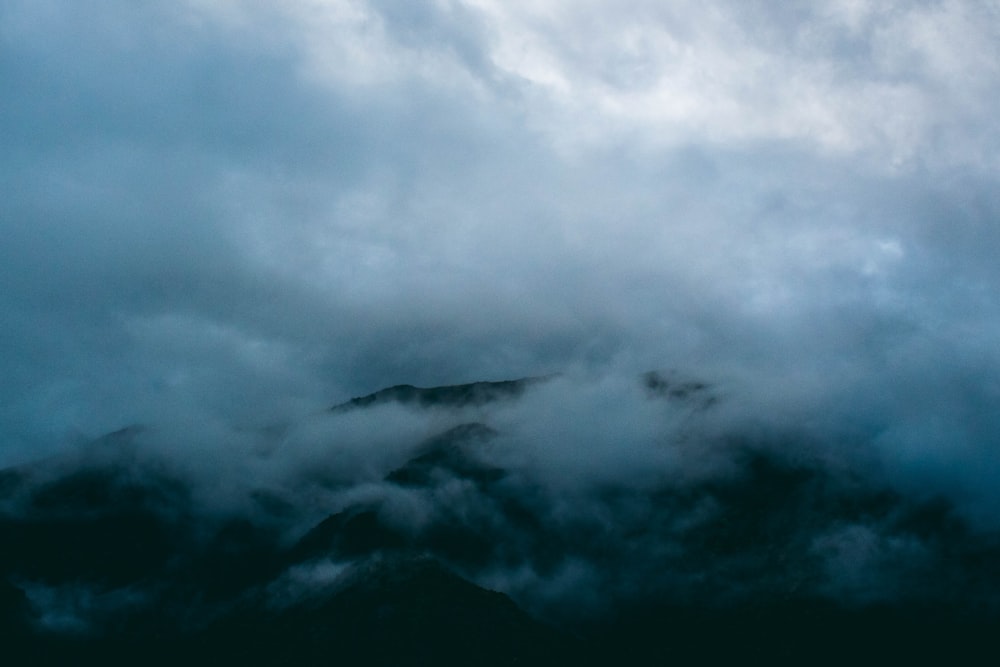 a mountain covered in clouds under a cloudy sky