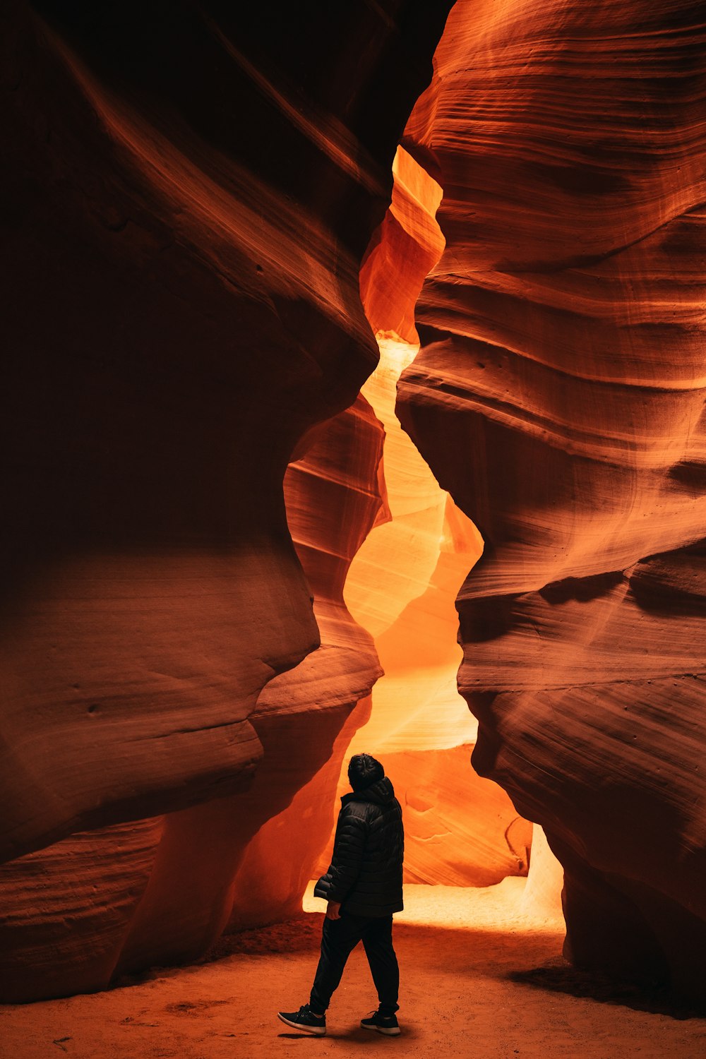 a person walking through a narrow slot in a canyon