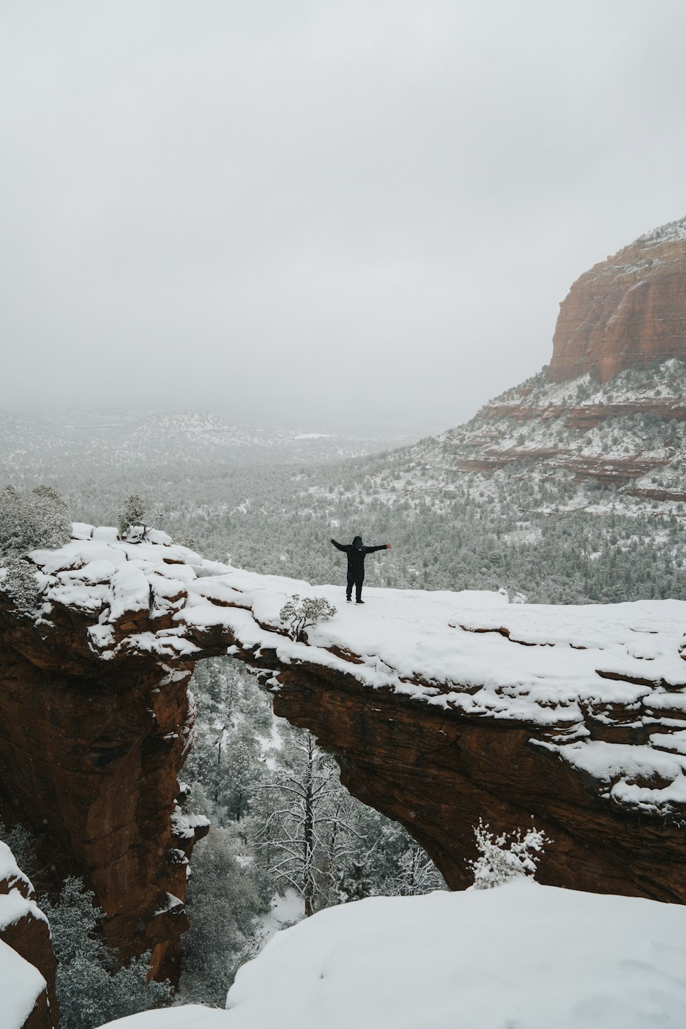 a man standing on top of a snow covered cliff