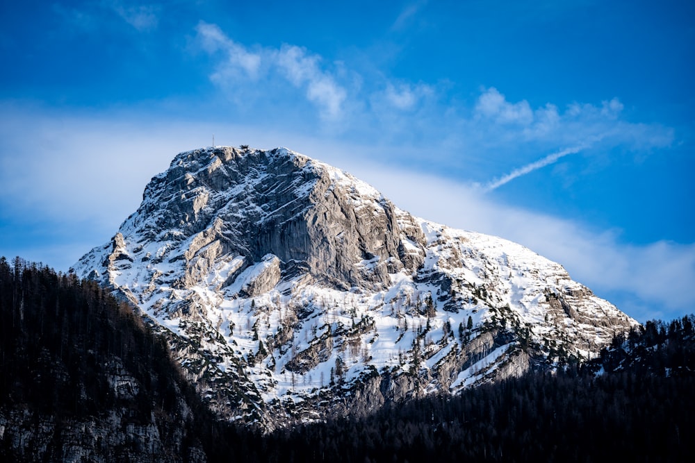 a snow covered mountain in the middle of a blue sky