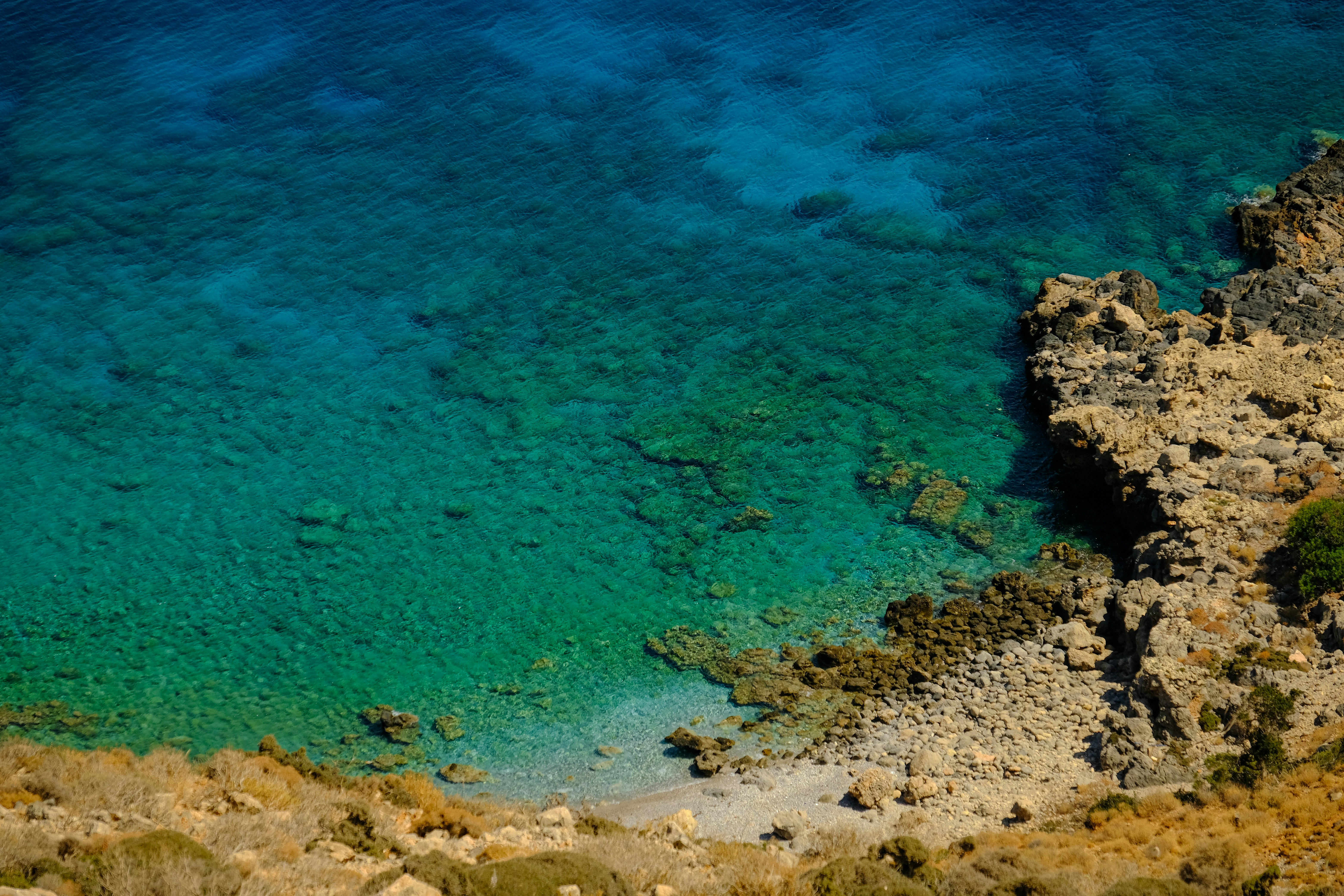 a body of water surrounded by rocks and grass