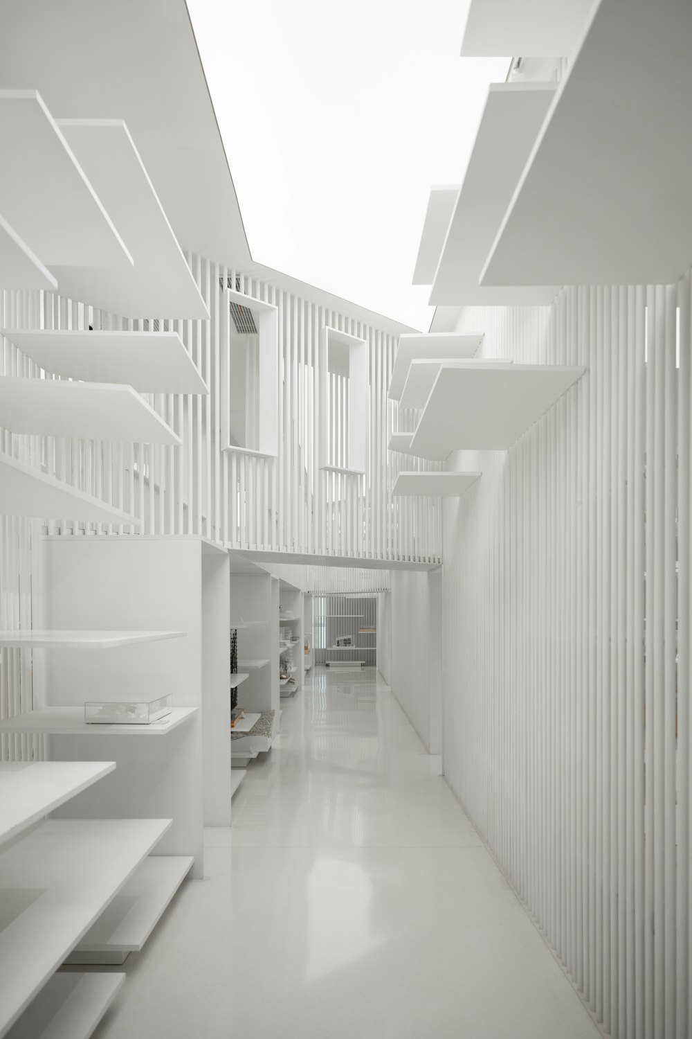 un largo pasillo blanco con estanterías y escaleras