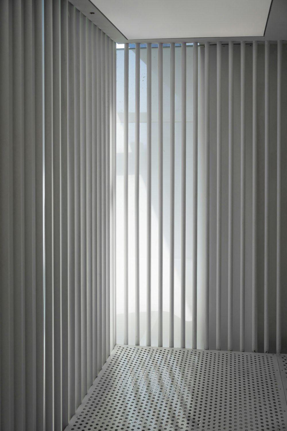 um quarto branco com persianas verticais e piso frio