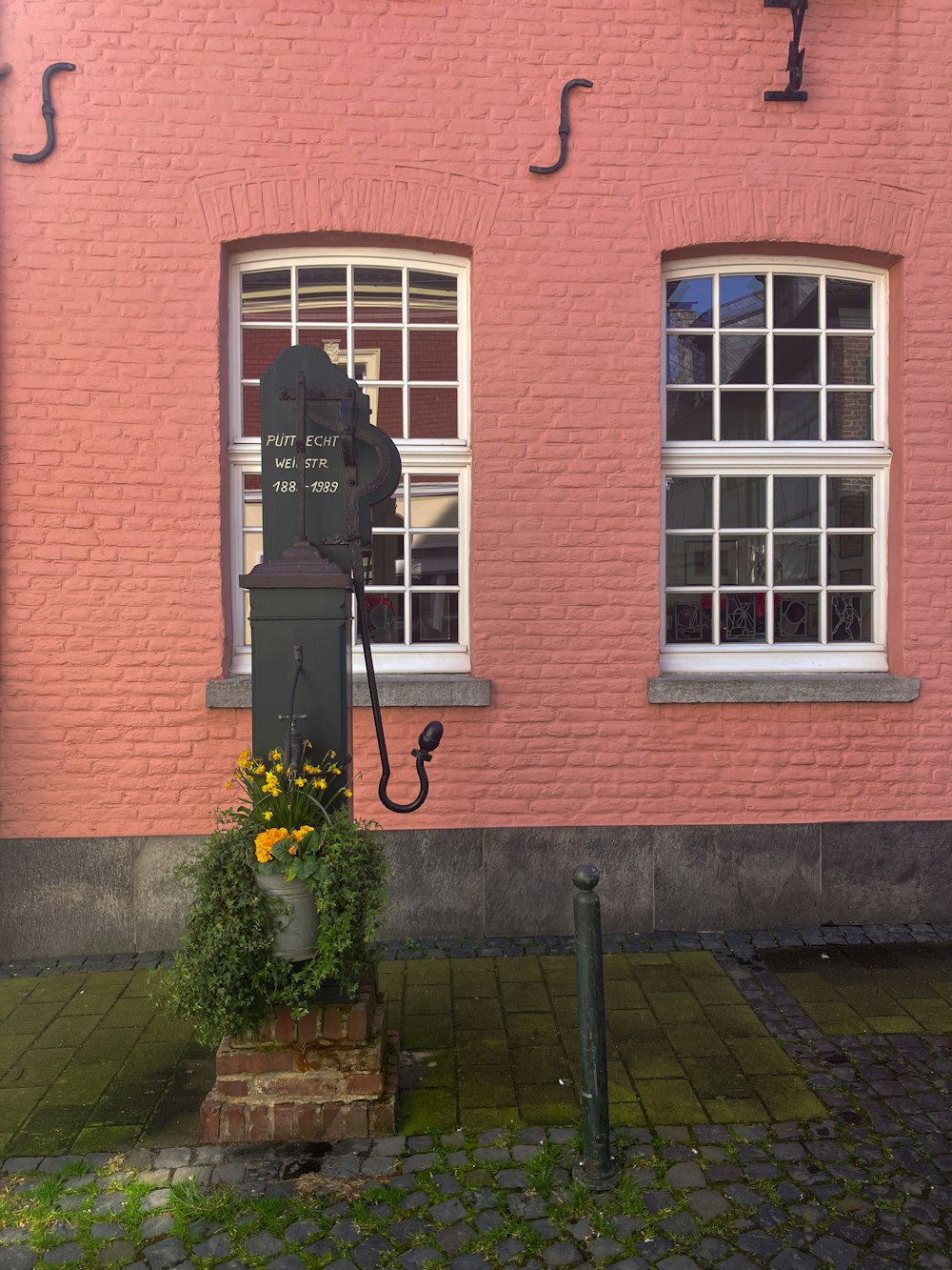 a pink brick building with two windows and a telephone