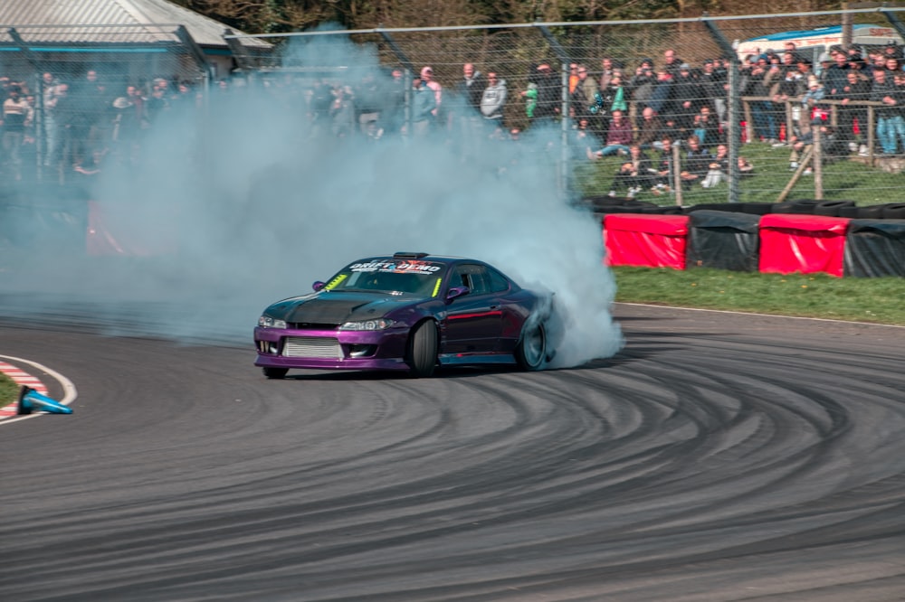 a car with smoke coming out of it driving on a track