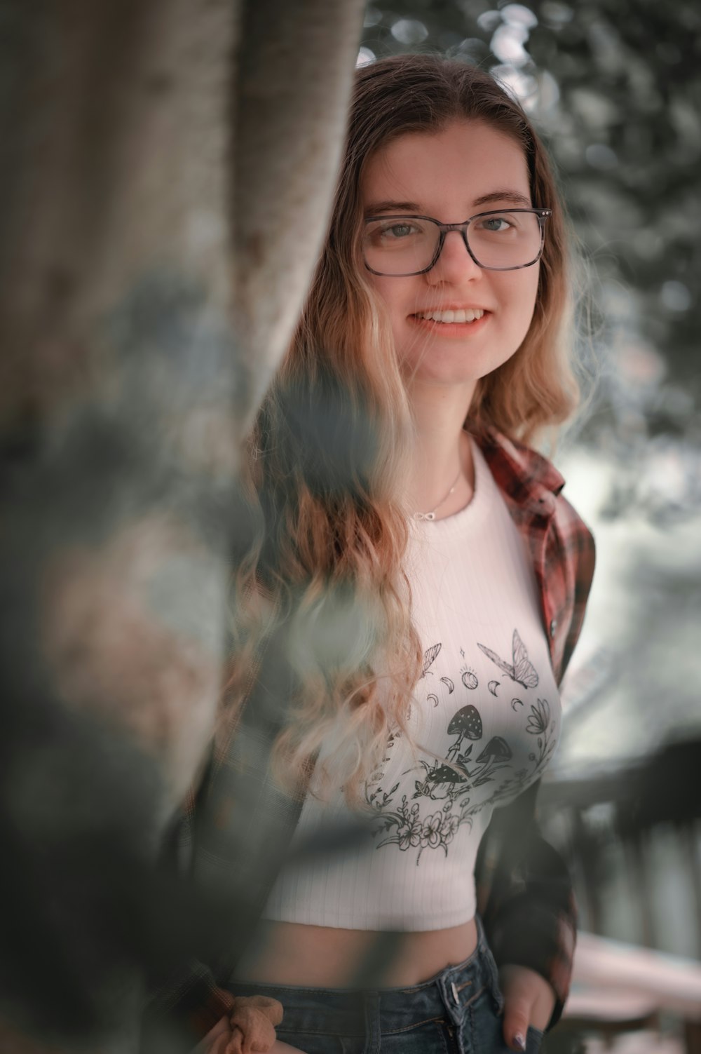 a woman wearing glasses standing next to a tree