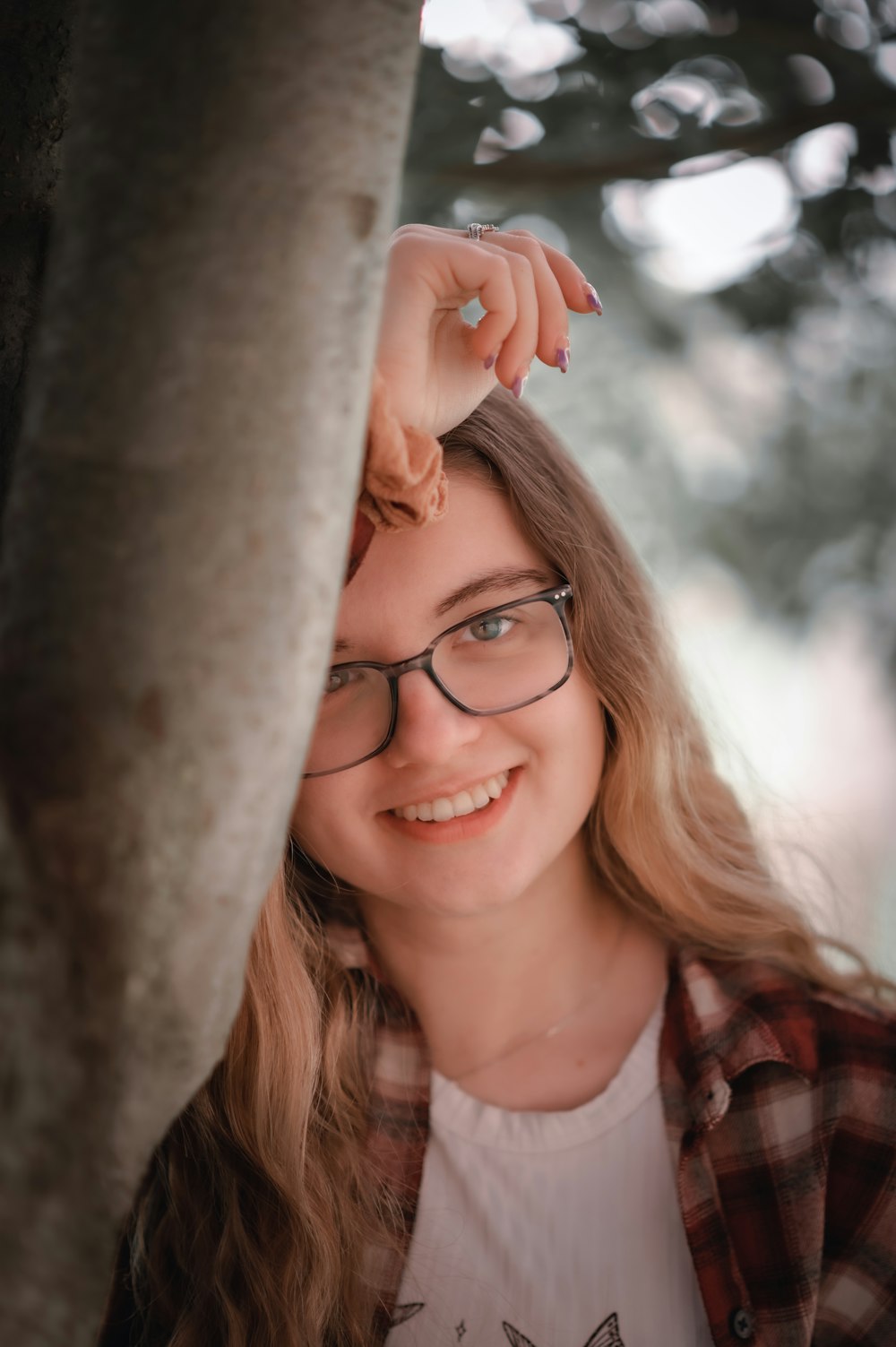 a woman wearing glasses standing next to a tree