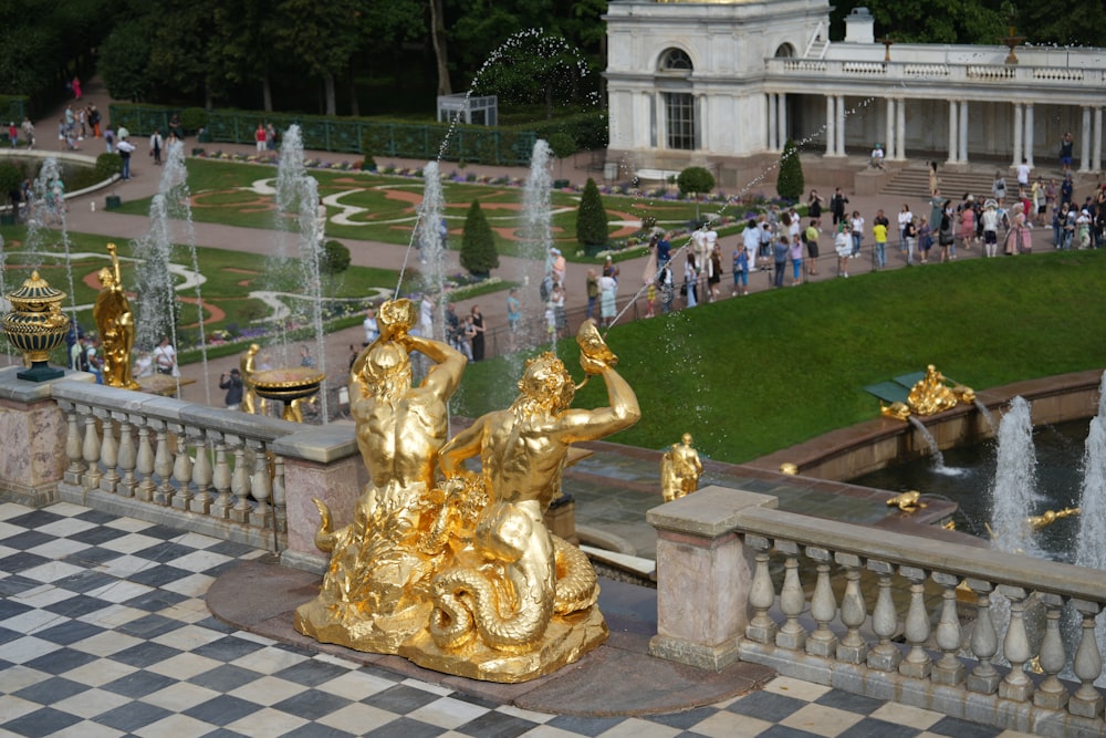a golden statue in front of a fountain in a park