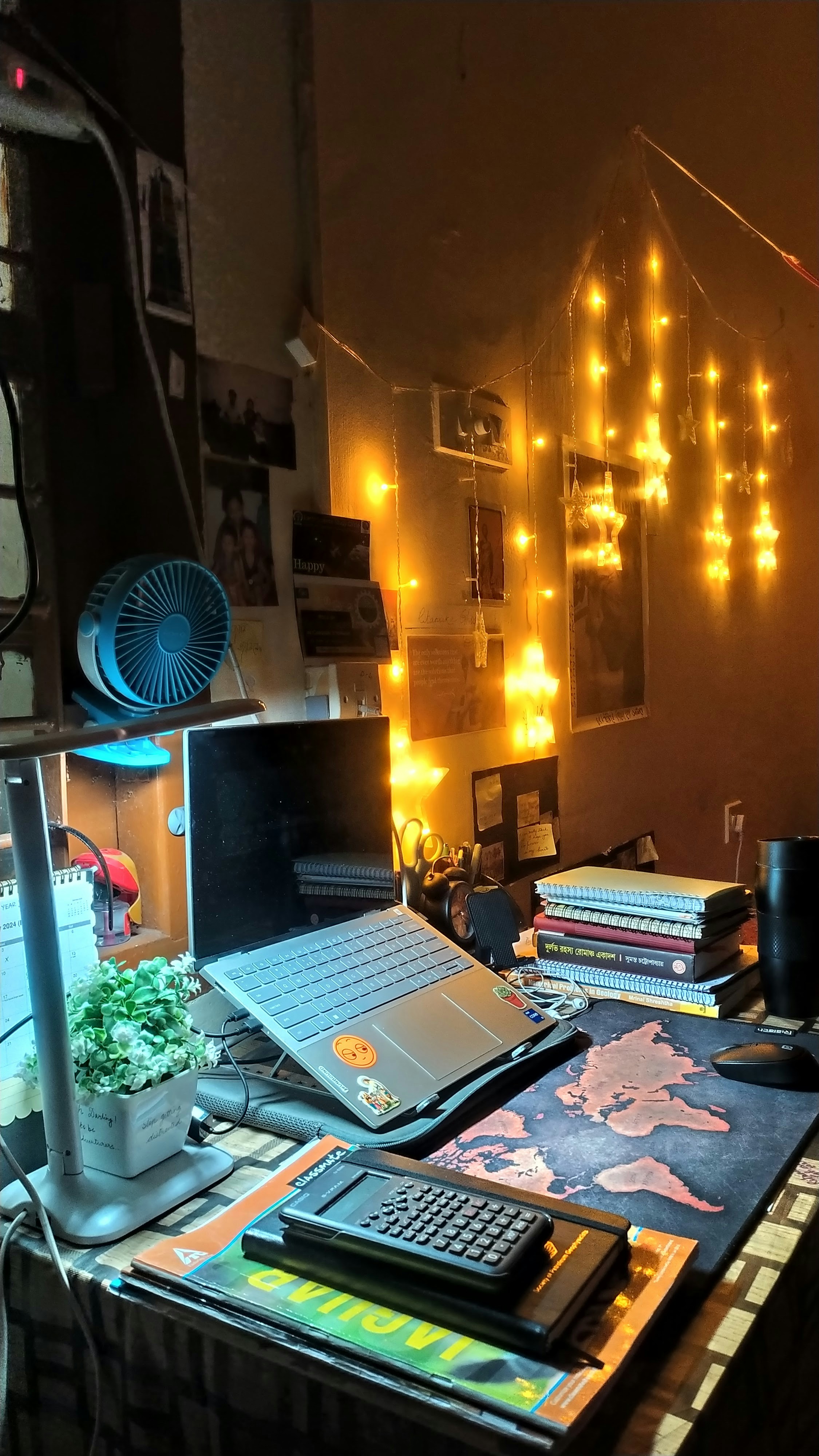 Open laptop with Python code editor, warm amber desk lamp, books stacked beside it, cozy dark study room atmosphere