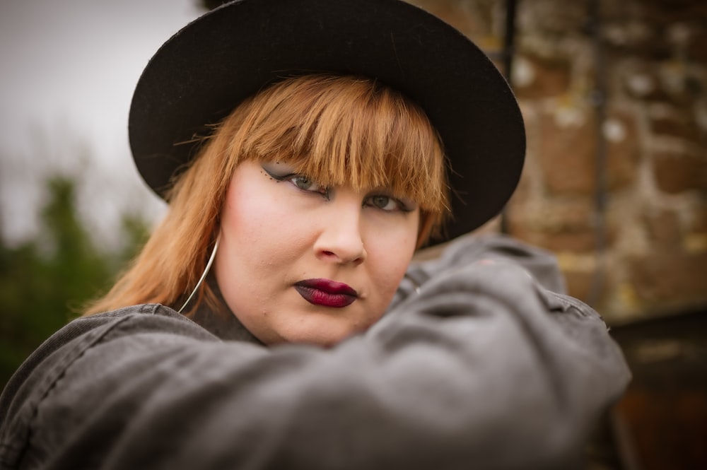 a woman with red hair wearing a black hat