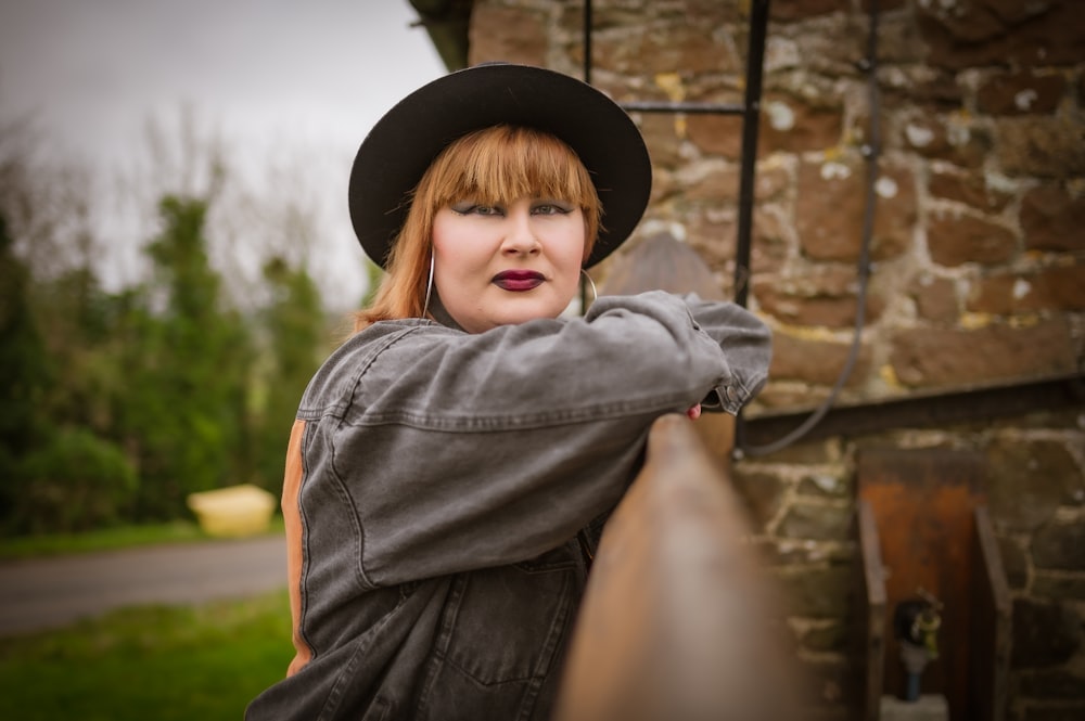 a woman wearing a hat leaning on a rail